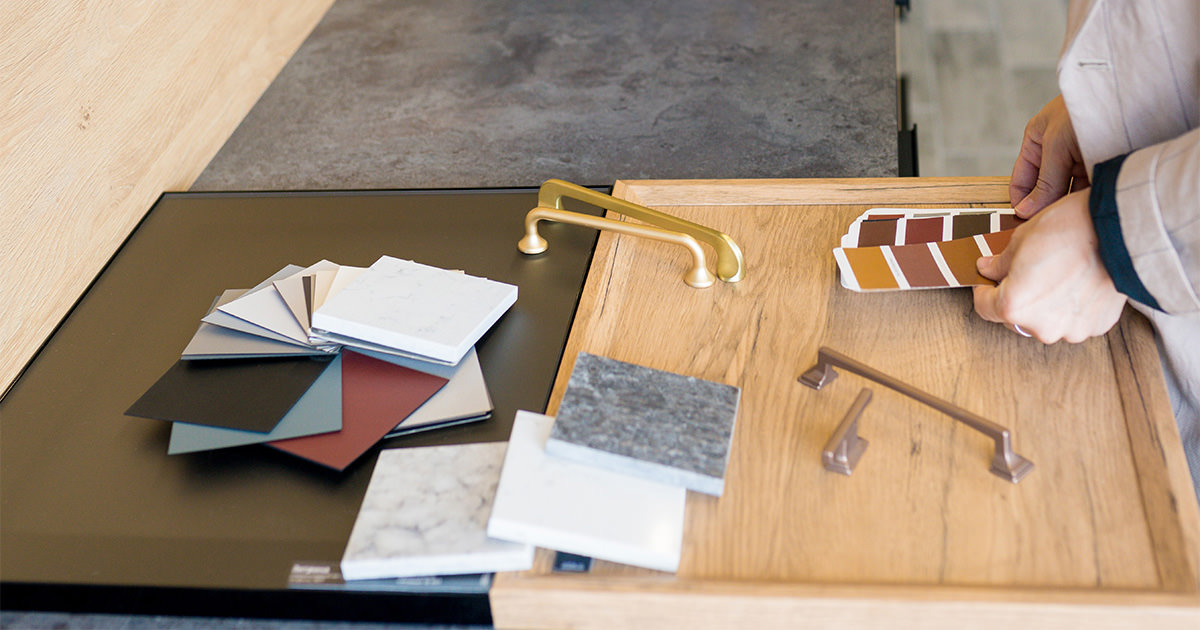How To Choose A Kitchen Cabinet Color Tips From A Designer Image 9 person picking out swatches of paint, counters, cabinets, and more for their kitchen design.