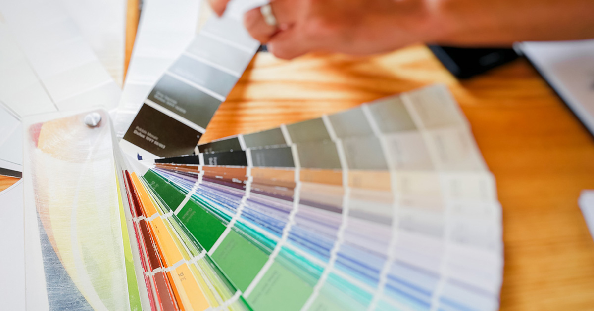 PMV - Blog - Working With An Interior Paint Color Consultant Person flipping through paint swatch books