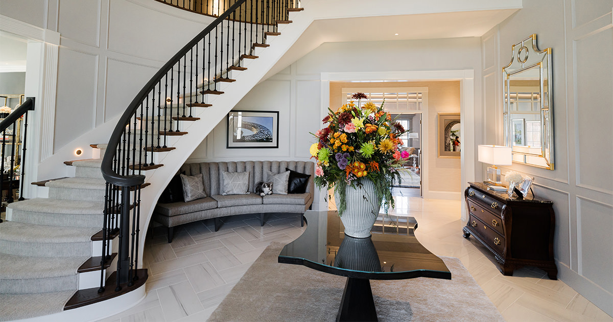 PMV - Project Highlight - Contemporary Lakehouse Header Entry way of large home with large vase of flowers and round stairs.